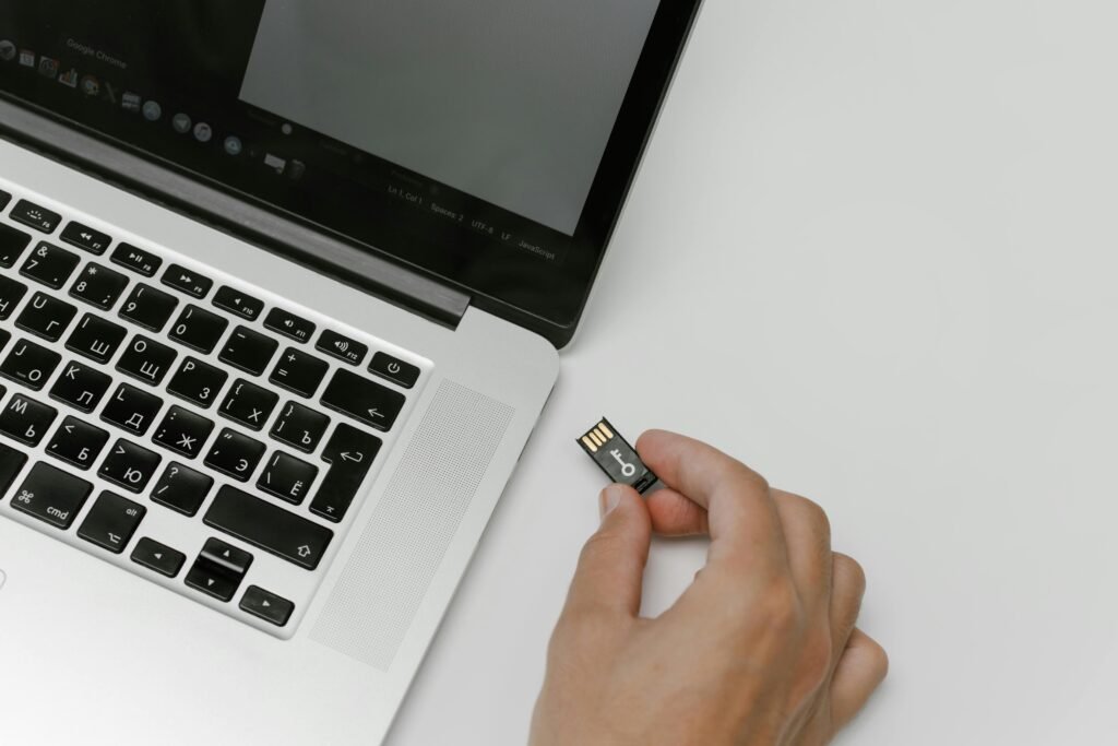 Person's hand inserting a USB flash drive into a laptop. Technology and data transfer concept.